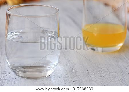 Closeup Glass Of Fresh Water And Juice At The Background/ Conceptual Image Of Half Full-half Empty G