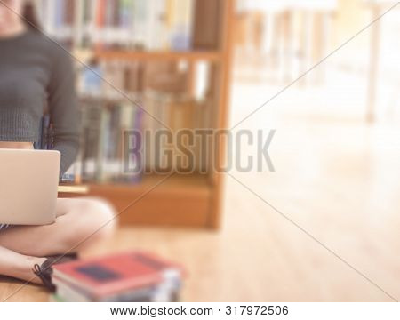 Hipster Young Woman Typing Modern Laptop In Library For Working Or Learning With Bookshelves At Back