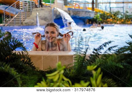Young Caucasian Girl With Pigtails Swimming In The Pool In A Closed Winter Water Park. Having A Good