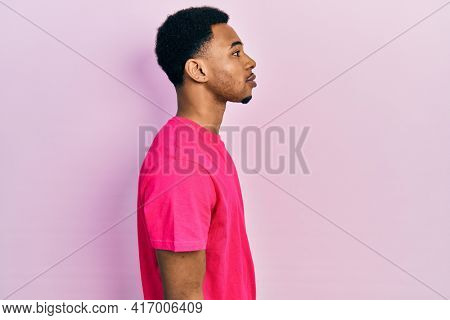 Young african american man wearing casua t shirt looking to side, relax profile pose with natural face with confident smile. 