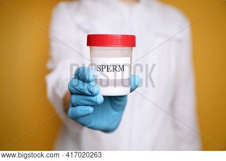 Scientist Holding Container With Sperm On Yellow Background, Closeup