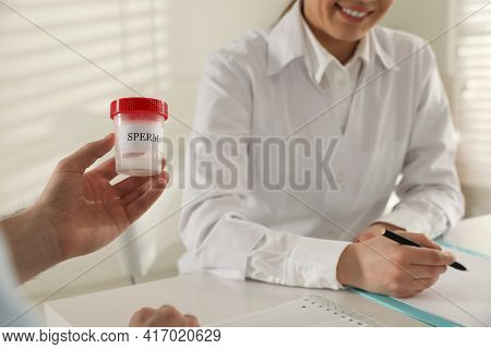 Donor Giving Container Of Sperm To Doctor In Hospital, Closeup