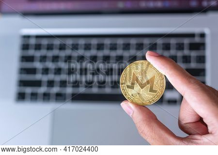 Businessman Hand Hold Golden Monero (xmr) Cryptocurrency Coin Over Keyboard Laptop, Monero Coin. Cry
