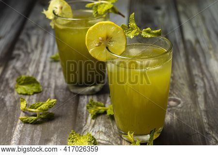 Selective Focus On Glass Of Mint Leaves Juices Garnished With Lemon Slices On Wooden Table