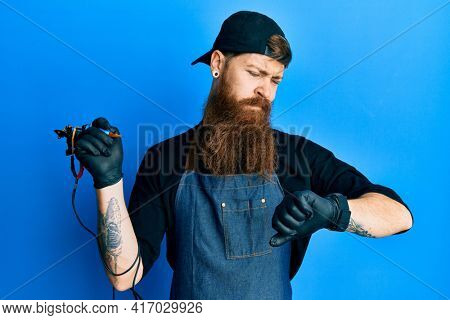 Redhead man with long beard tattoo artist wearing professional uniform and gloves checking the time on wrist watch, relaxed and confident 