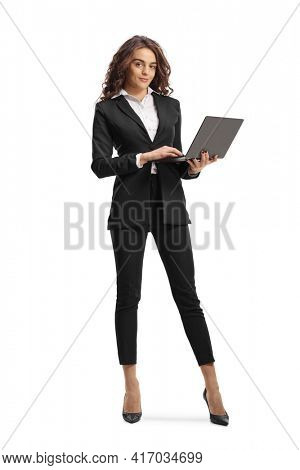 Full length portrait of a young businesswoman standing and working on a laptop computer isolated on white background