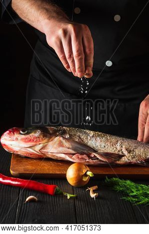 The Cook Prepares Fresh Fish Bighead Carp Sprinkling Salt With Ingredients. Preparing To Cook Fish F