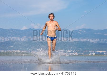 Man lopen over het strand in blauwe badpak