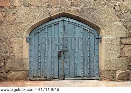 Ancient Stone Wall With A Gate In The Old Castle. Wooden Gate Of A Medieval Castle