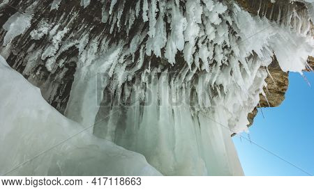 Bizarre Icicles Hang From The Ceiling Of A Stone Grotto In The Rock, Like Stalactites. Texture Of Ic