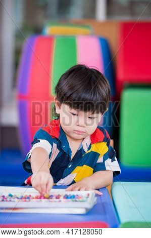 Portrait Vertical Image Of Baby Boy Picking Up Chalk Colors For Crafting On The Table. Son Doing Art