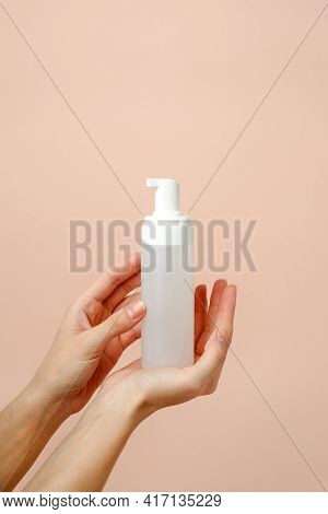 Female Hand With Cosmetic Product In Bottle On Neutral Beige Trendy Background, Concept Of Helathcar