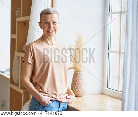 Portrait Of Attractive Happy Middle Aged Woman In Casual Wear Keeping Hands In Jeans Pockets And Smi