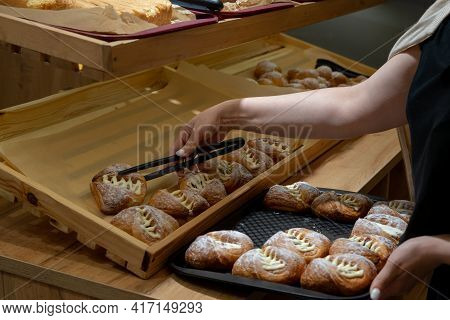 An Employee Of A Bakery, Self-service Restaurant, Lays Out Buns On A Distribution Line. Copispace.