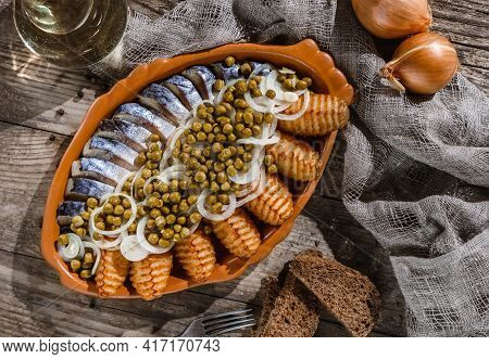 Fried Potatoes With Herring Fish Slices, Canned Green Peas And Onions In Plate On Wooden Rustic Tabl