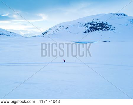Cross Country Skier Traveling Across A Snowy Arctic Tundra In The High Mountains On A Cold Winters D
