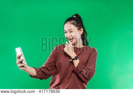 A Beautiful Young Woman Is On A Video Call With Someone Holding Her Chin Face And Laughing With A Ha