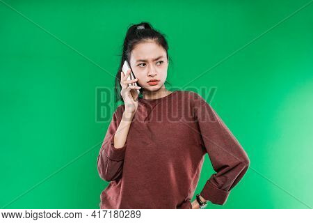 Beautiful Young Asian Woman Talking On Phone While Looking Beside With Angry Expression