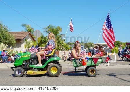 Young Girls With American Flag Riding Small Lawn Mower And Parading At The 4th Of July Independence 