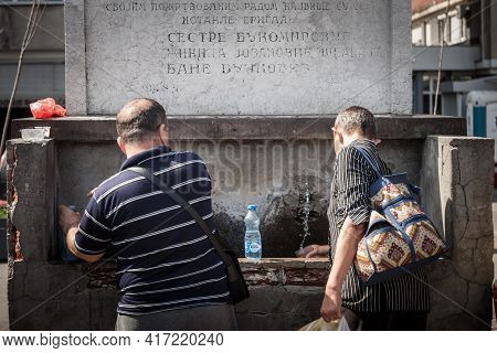 Belgrade, Serbia - June 8, 2019: Two Men Filling Bottles And Drinking Water At A Public Drinking Fou