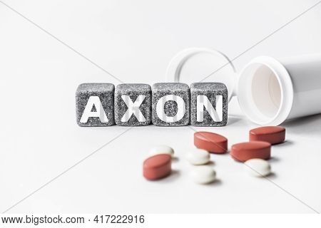 Word Axon Is Made Of Stone Cubes On A White Background With Pills. Medical Concept Of Treatment, Pre