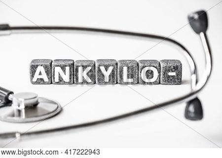 Stone Block Form Word Ankylo With Stethoscope. White Background. Medical Concept. Crooked Or Bent Re