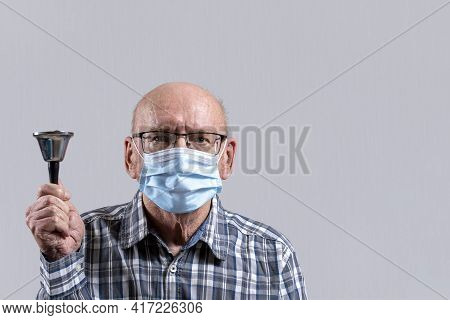 Old Bald Man With Glasses And Medical Mask With Bell In His Hand. Copy Space.