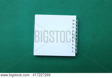 Blank White Spiral Notepad On A Desk Green Background.eucation And Business Concept