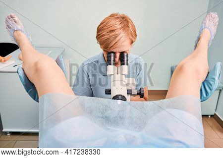 Front View Of Doctor In Blue Shirt Examining Woman With Colposcope In Gynecological Clinic. Female P