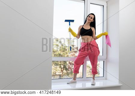 Smiling Young Woman Cleaning Windows. Housekeeping Theme.