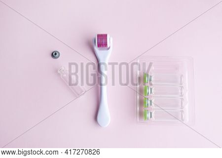 Dermaroller, Mesoscooter, Gold Microneedles And Hyaluronic Acid Ampoules On A Pink Background. Anti-