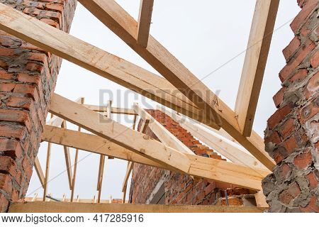 Installation Of Wooden Beams At Construction The Roof Truss System Of The Brick House.