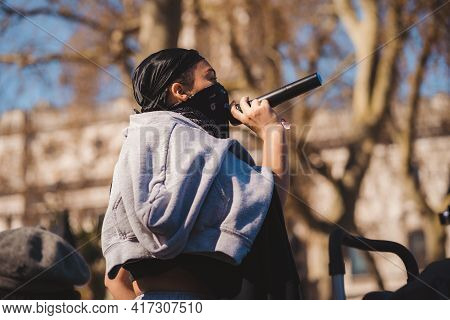Westminster, London | Uk -  2021.04.17: Person With Microphone In Black Bandana Over Her Face Giving