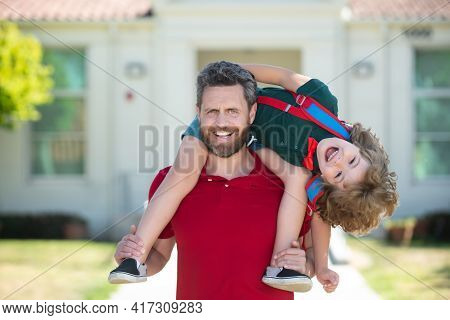 Parent Supports And Motivates Son. Father Giving Son Piggyback Ride After Come Back From School.