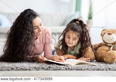 Children Development Concept. Loving Young Mom Reading Book To Her Little Daughter