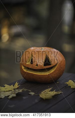 Pumpkin With Glowing Eyes And A Skull On Wooden Background. Sinister Halloween.