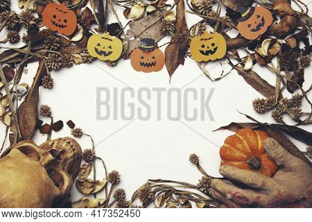 Pumpkin With Glowing Eyes And A Skull On Wooden Background. Sinister Halloween.