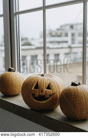 Pumpkin With Glowing Eyes And A Skull On Wooden Background. Sinister Halloween.
