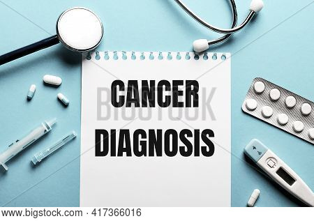 The Words Cancer Diagnosis Written On A White Notepad On A Blue Background Near A Stethoscope, Syrin