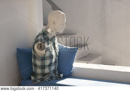 Bust Of An Armless Mannequin Wearing A Shirt Over Pillows, Near A Stone Staircase In A Village On A 