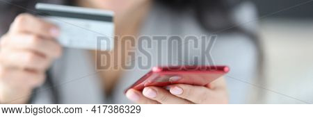 Woman Holding Bank Card And Phone In Her Hands Close-up