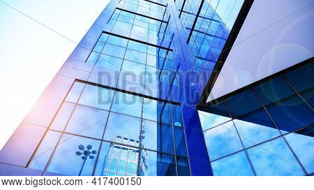 Tytuł: Bottom View Of Modern Skyscrapers In Business District Against Blue Sky. Looking Up At Busine