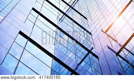 Tytuł: Bottom View Of Modern Skyscrapers In Business District Against Blue Sky. Looking Up At Busine