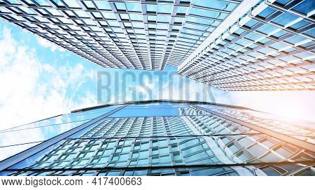 Bottom View Of Modern Skyscrapers In Business District Against Blue Sky. Looking Up At Business Buil