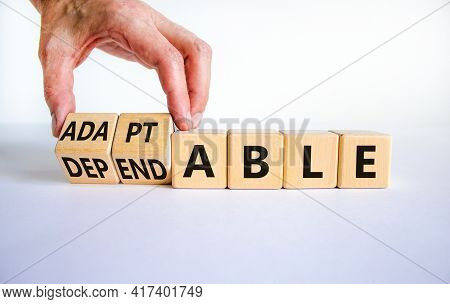 Adaptable Or Dependable Symbol. Businessman Turns Wooden Cubes And Changes The Word Dependable To Ad