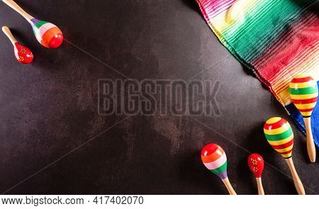 Cinco De Mayo Holiday Background Made From Maracas, Mexican Blanket Stripes Or Poncho Serape On Dark