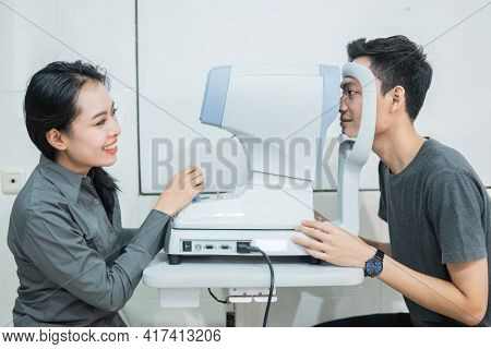 A Female Doctor And A Male Patient Doing An Eye Check Using A Device
