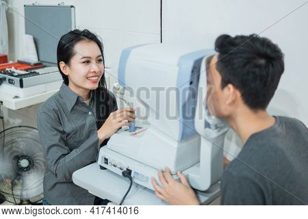 A Female Doctor And A Male Patient Doing An Eye Check Using A Device