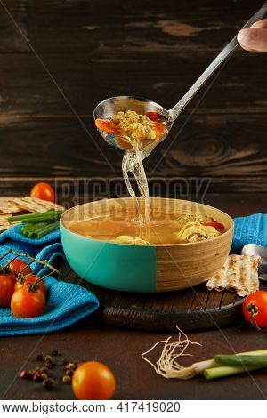 Soup With Matzo Dumplings And Chicken With Carrots And Tomatoes Is Poured Into Bowl With Ladle. Heal