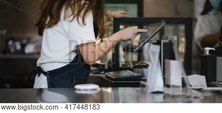 Side View Of A Young Asian Woman Touching On The Digital Tablet To Recive Order From Customer In Cof